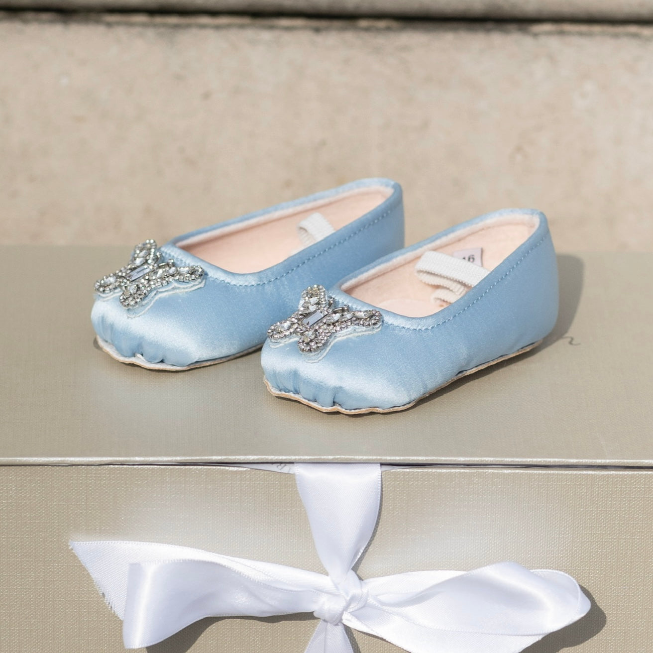 Handcrafted blue pre-walker baby flower shoes, combining delicate lace and satin for luxury flower girl looks.
