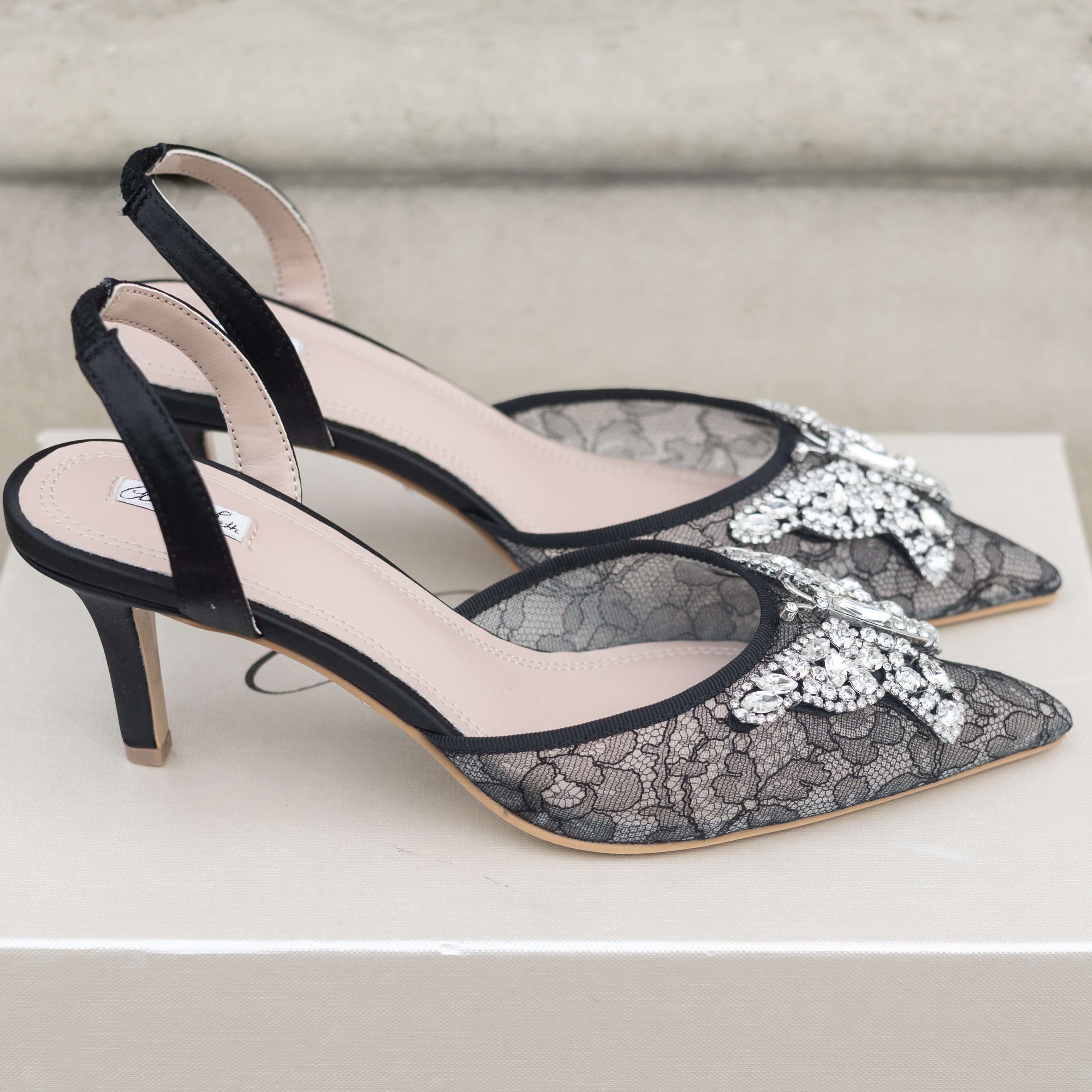 Black lace high-heeled shoes on a light gray background